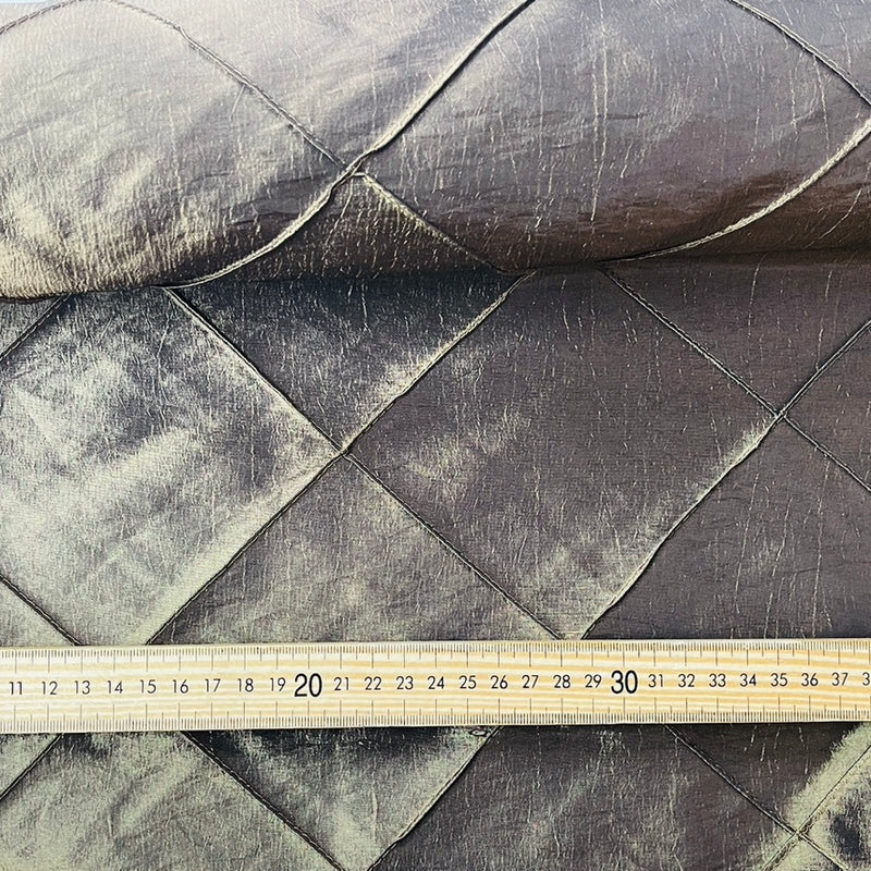A close-up of dark brown quilted fabric with a diagonal ruler laid across the bottom to show scale.