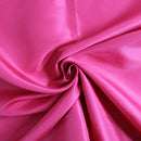 A close-up of bright pink dress lining fabric arranged in a spiral drape, showing a smooth, glossy texture.