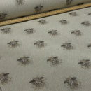 A close-up of patterned fabric with a repeating cow print on a light beige background, with a wooden ruler placed along the top edge for scale.