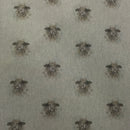 A close-up of fabric featuring a repeating pattern of sheep heads in muted brown and gray tones on a light warm gray background.