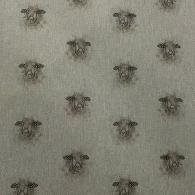 A close-up of fabric featuring a repeating pattern of sheep heads in muted brown and gray tones on a light warm gray background.