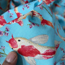 Fabric with fish and floral pattern held by a hand