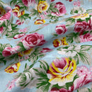 Floral fabric with pink, yellow, and green flowers on a light blue background
