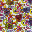 A close-up of a colorful fabric or wallpaper pattern featuring sugar skulls, peace signs, butterflies, hearts, and swirls on a white background.