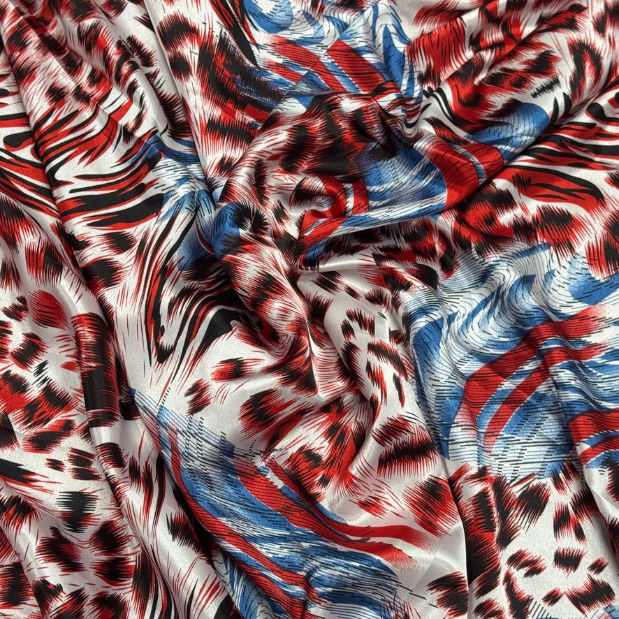 A close-up of draped fabric with an abstract animal-inspired print in red, black, blue, and white.