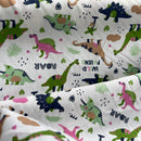 Fabric with colorful dinosaur pattern on a cream background