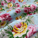 Close-up of floral fabric with pink, yellow, and green flowers on a light blue background.