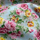 Floral fabric with pink roses and yellow flowers on a light blue background