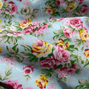 Floral fabric with pink, yellow, and green flowers on a light blue background