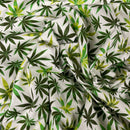 A close-up of draped fabric featuring an all-over cannabis leaf print on a light cream background.