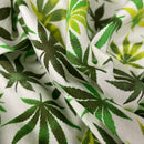 White fabric with a green and dark green cannabis leaf pattern, shown in a close-up draped view.