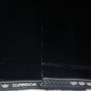 Close-up of a black fabric material with a white stitched border and the word 'SUPERIOR' printed along the edge, alongside small crown motifs.