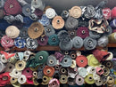 A dense collection of rolled fabrics in various colors and patterns, stacked tightly together on shelves.