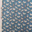 A close-up of fabric showing a repeating chicken print on a medium blue background. The chickens are illustrated in white with black speckles and linework, with some gray chickens.